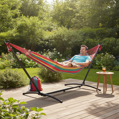 Personne se relaxant sur un hamac sur pied SOLARA multicolore dans un jardin ensoleillé